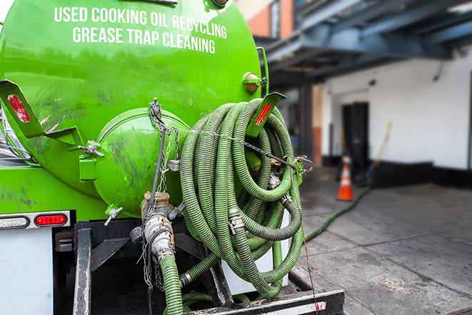 a technician pumping a grease trap in a commercial building in Cashion